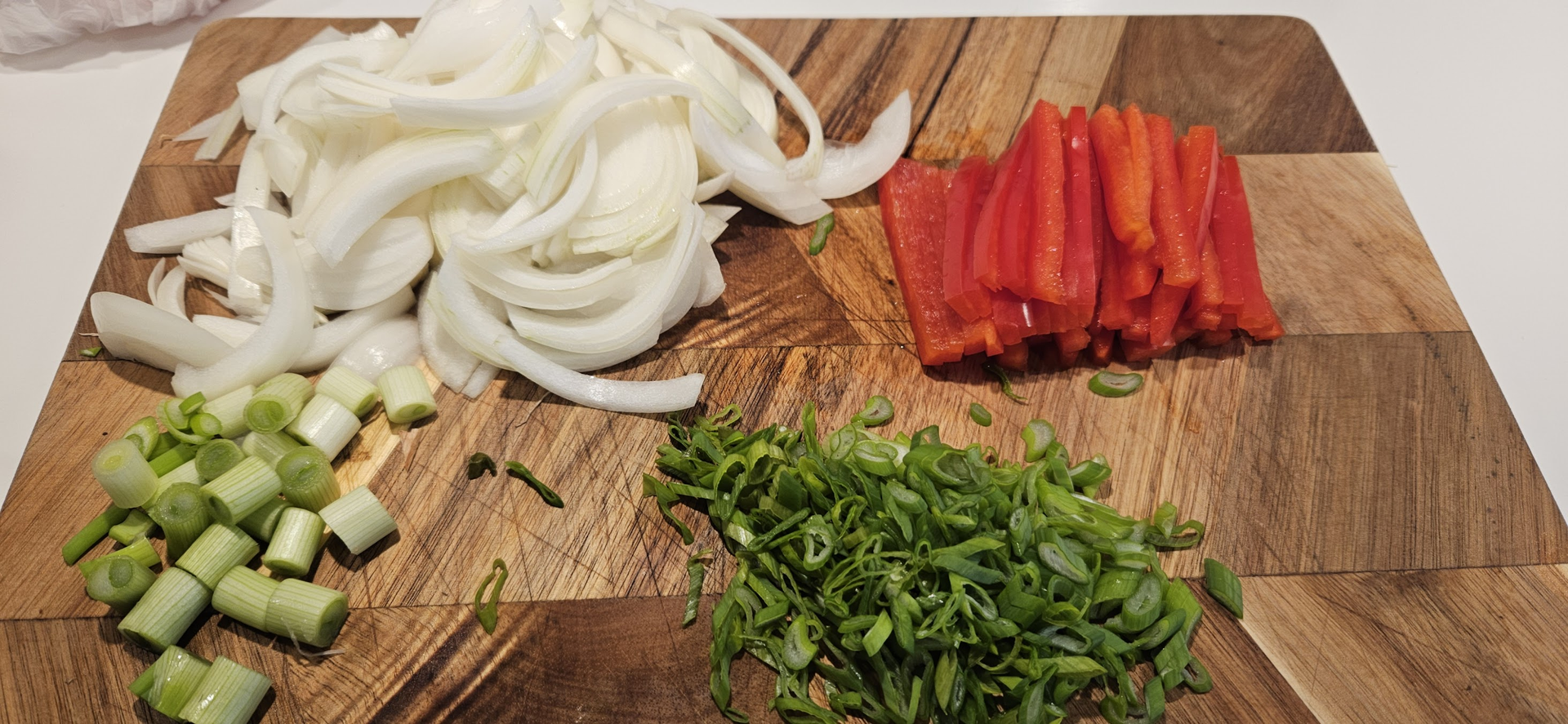 Kutt vårløk, løk og paprika, og la den grønne delen av vårløken vente til slutt.