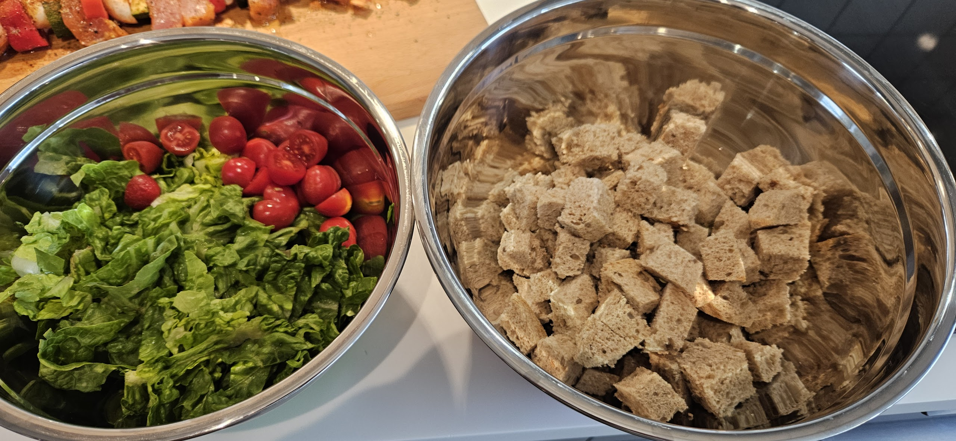 Skjær hjertesalat, del tomatene og vend brødterningene klare til krutonger.