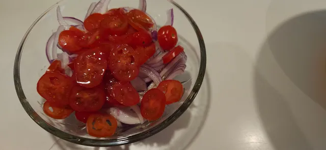 Lag en rask salat med rødløk og tomat mens du gjør klar resten av tilbehøret.