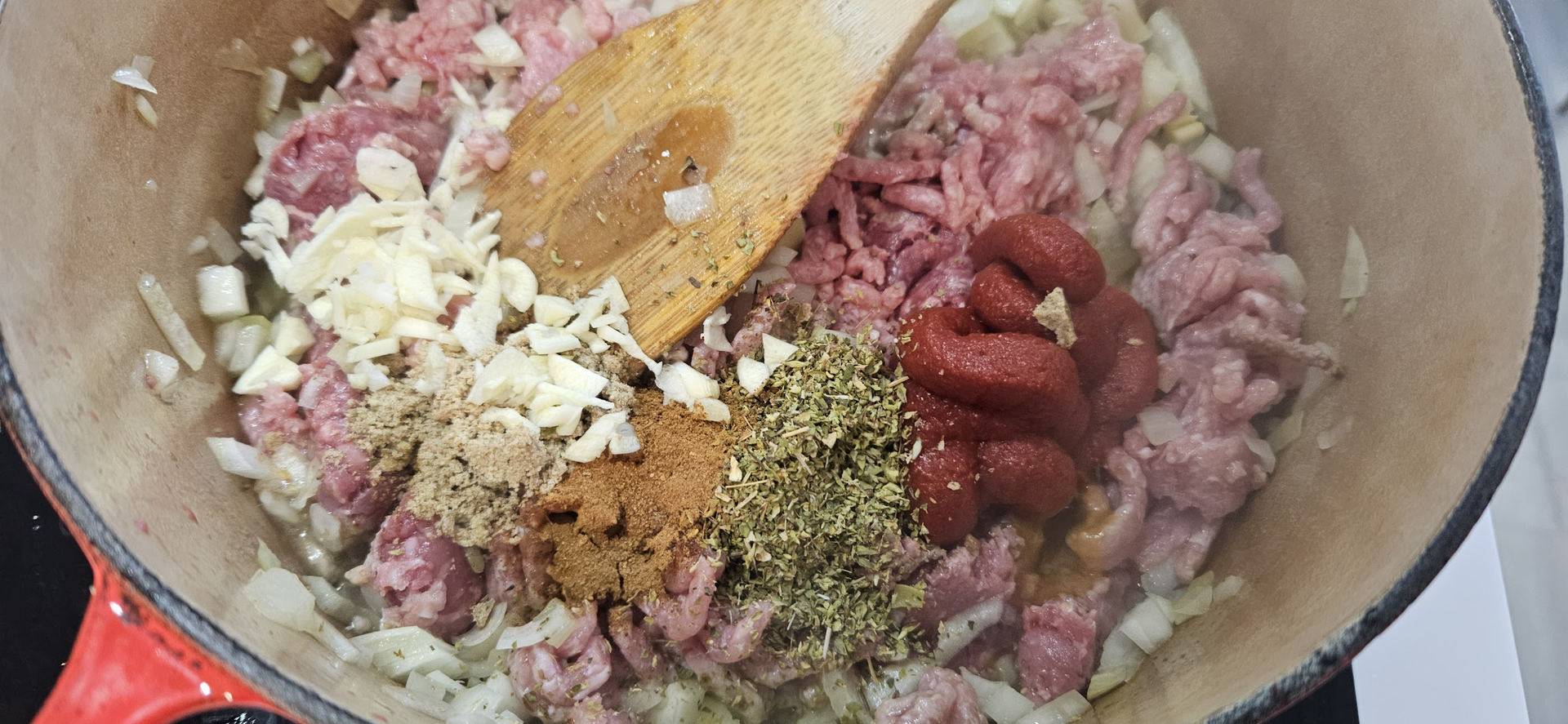 Tilsett oregano, hvitløk, tomatpuré, buljongterning og kanel mens kjøttet fortsatt steker.