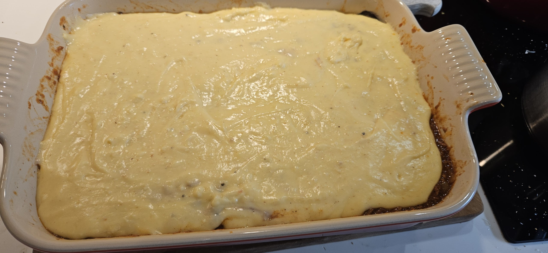 Dekk formen med bechamelsaus laget av smør, mel og melk, og rør inn muskattnøtt og revet parmesan.