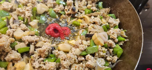 Når kjøttet og grønnsakene har fått farge: stek inn tomatpuré.