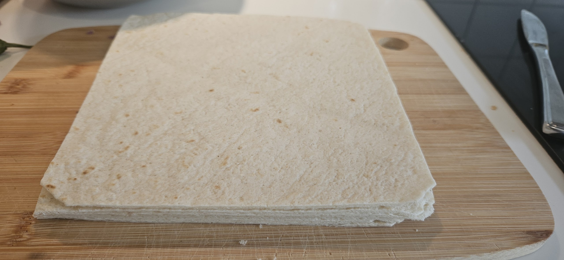 Ta hele pakken med hvetetortilla og skjær av kantene slik at det blir en firkant. Kantene kan du spare og bruke til hjemmelaget tortillachips hvis du steker dem i olje.