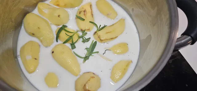 Potetmosen kokes i melk med to av hvitløksfeddene og litt rosmarin for en rund og god aroma.