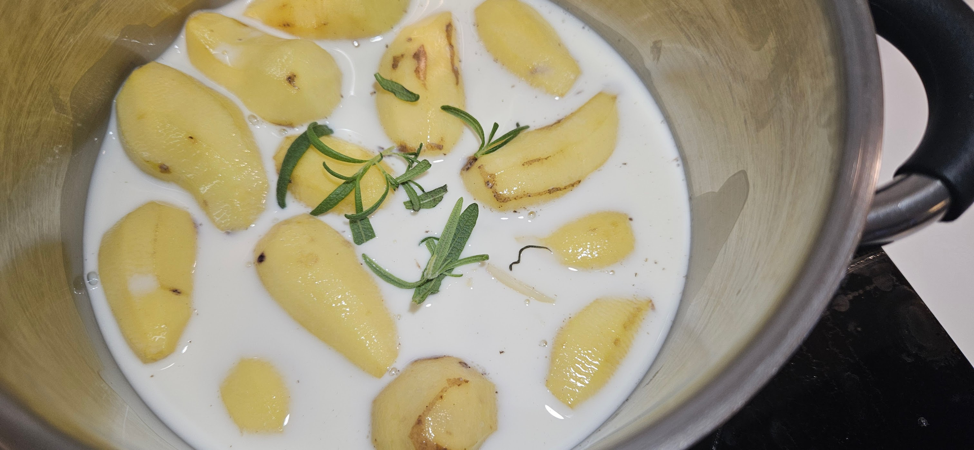 Potetmosen kokes i melk med to av hvitløksfeddene og litt rosmarin for en rund og god aroma.