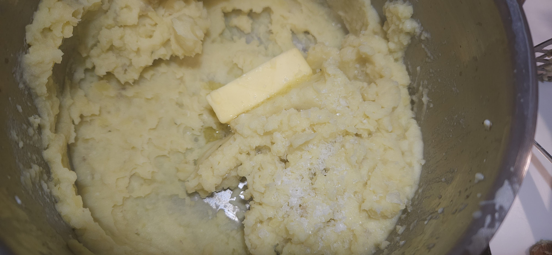 Når potetene er møre, moser du dem med smør og salt til en glatt og luftig potetmos.